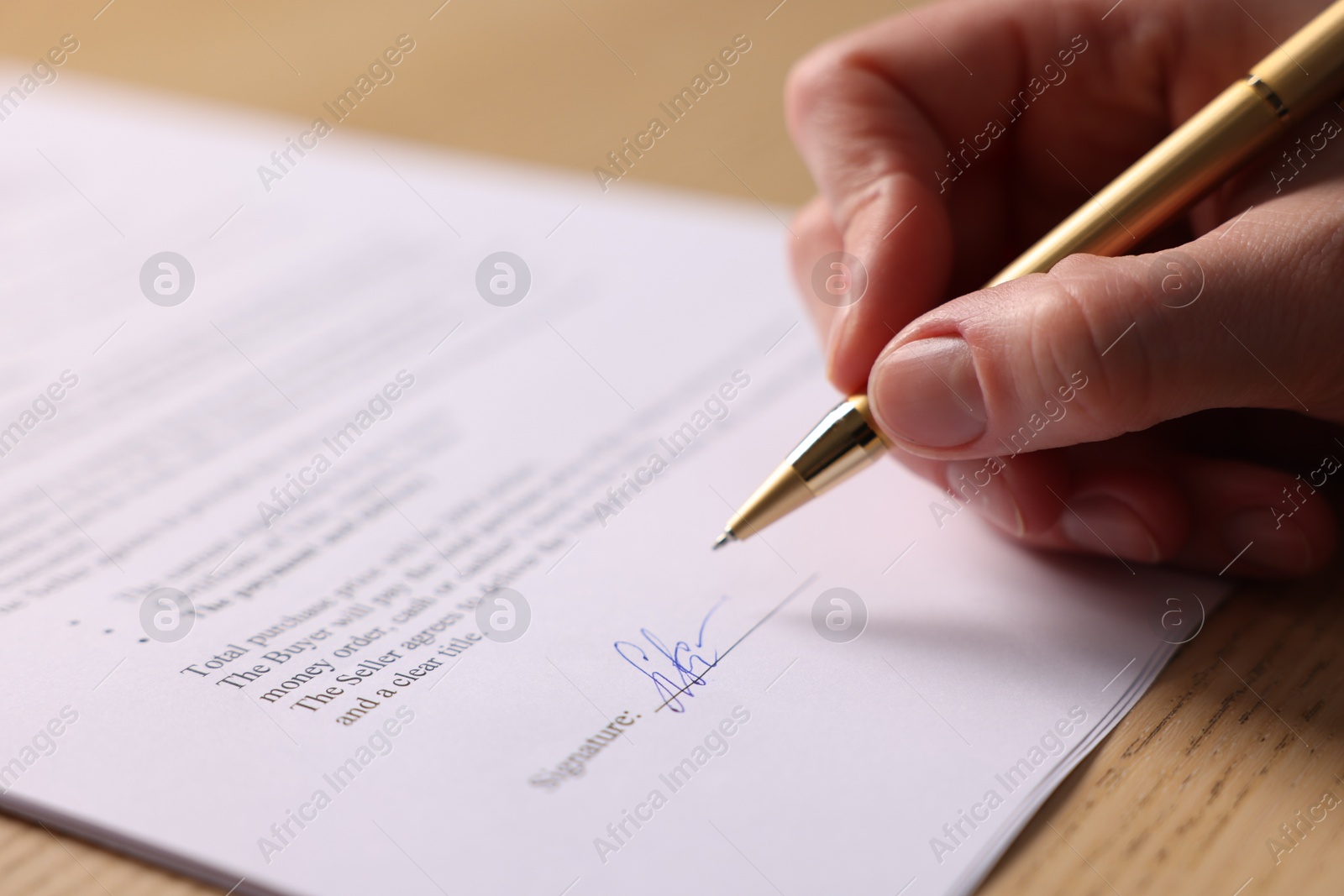 Photo of Woman putting signature on document at table, closeup