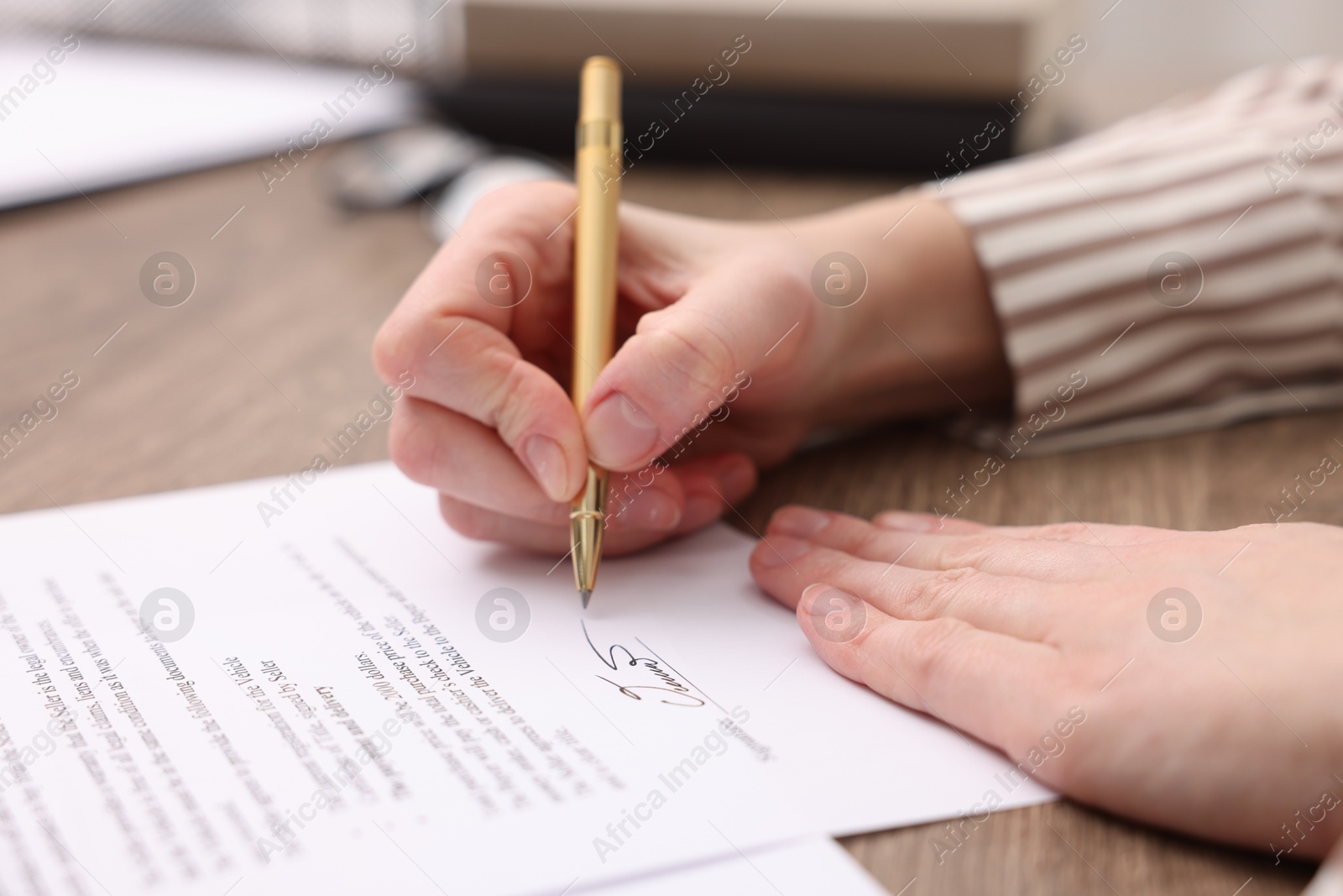 Photo of Woman putting signature on document at table, closeup