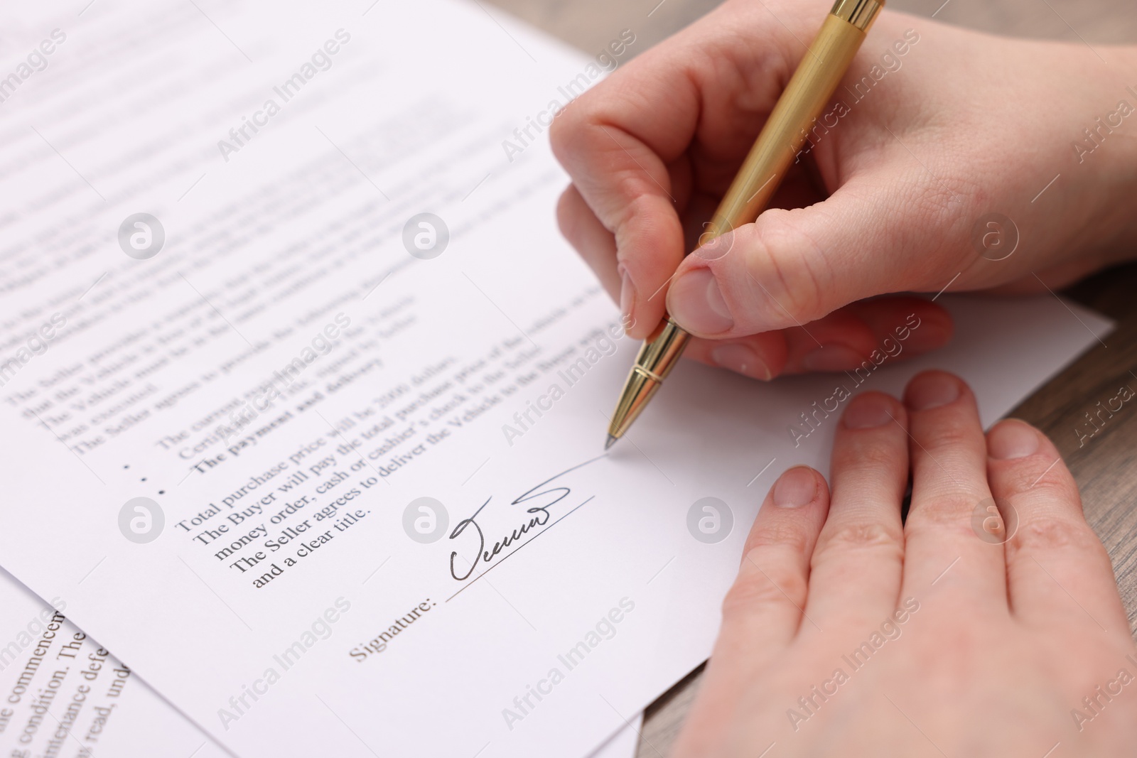 Photo of Woman putting signature on document at table, closeup