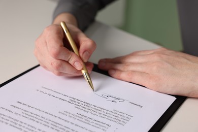 Photo of Woman putting signature on document at white table, closeup