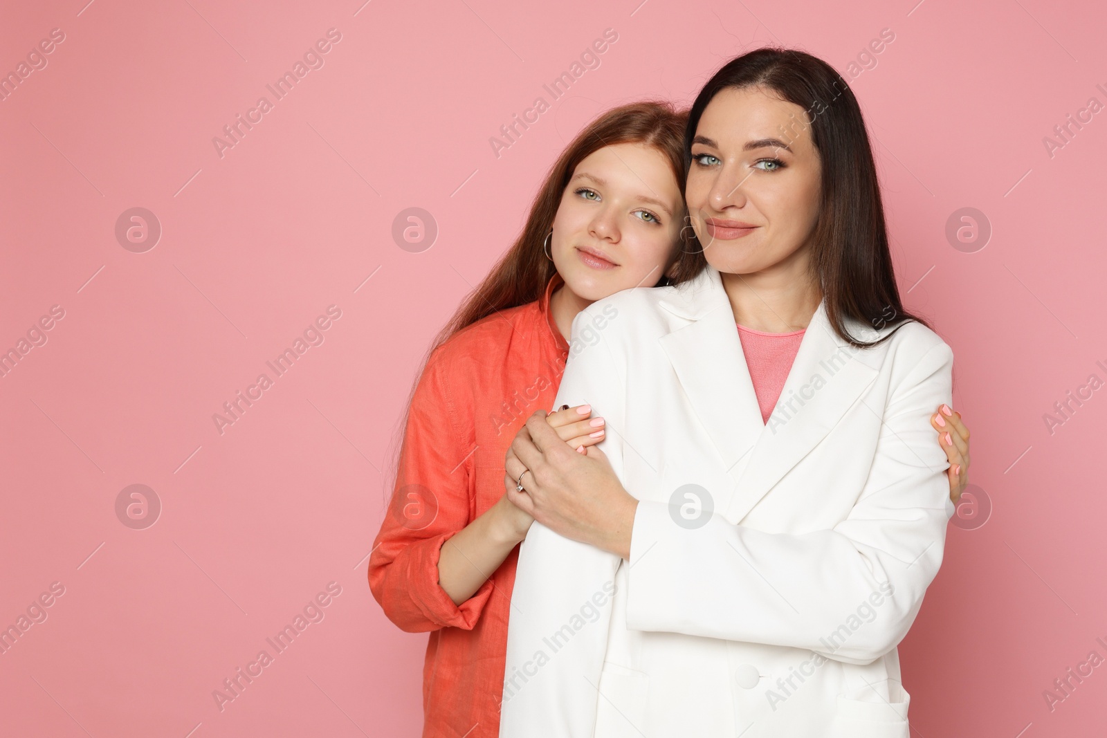 Photo of Portrait of beautiful mother with teenage daughter on pink background, space for text