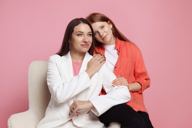 Photo of Portrait of beautiful mother with teenage daughter on armchair against pink background