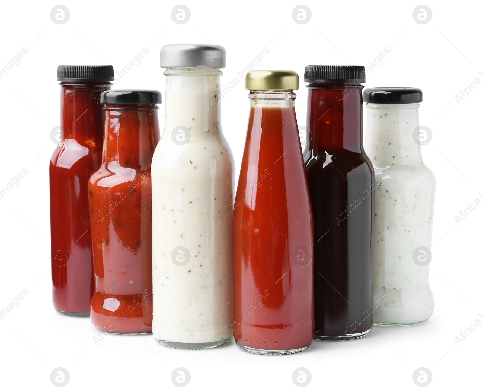 Photo of Different delicious sauces in glass bottles isolated on white