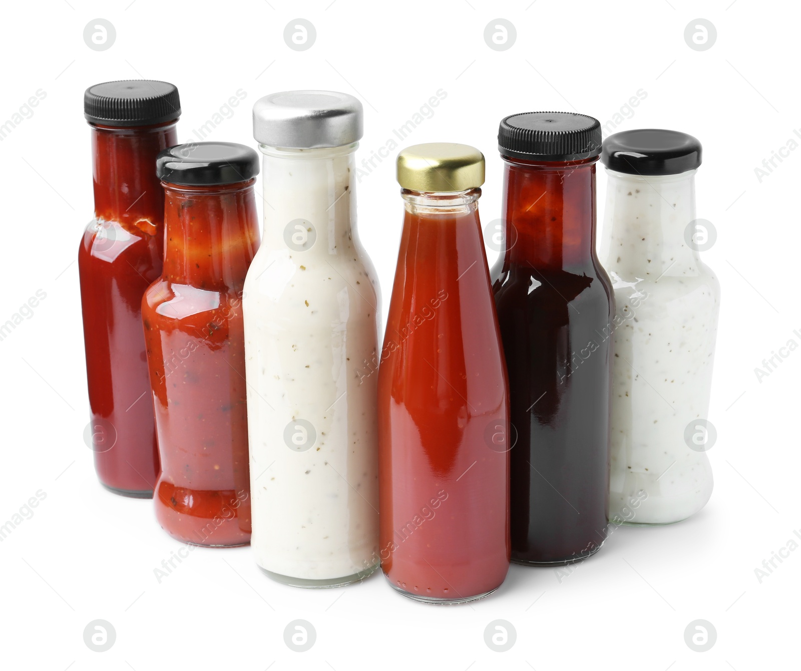 Photo of Different delicious sauces in glass bottles isolated on white