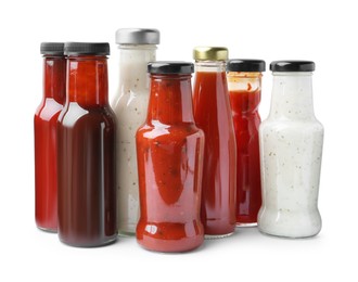 Photo of Different delicious sauces in glass bottles isolated on white