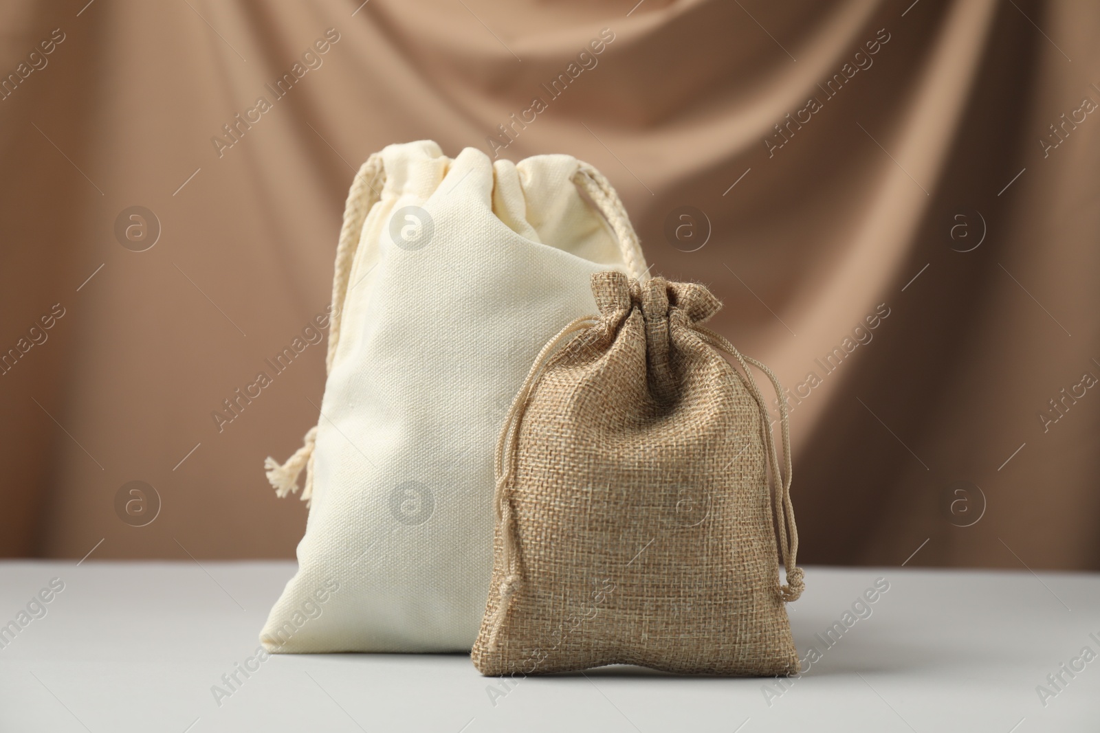 Photo of Burlap and cotton bags on white table against dark beige fabric