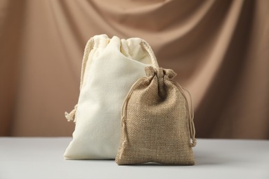 Photo of Burlap and cotton bags on white table against dark beige fabric