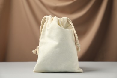 Photo of One cotton bag on white table against dark beige fabric