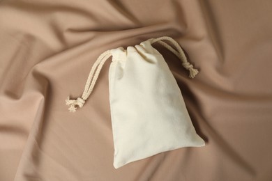 Photo of One cotton bag on dark beige fabric, top view