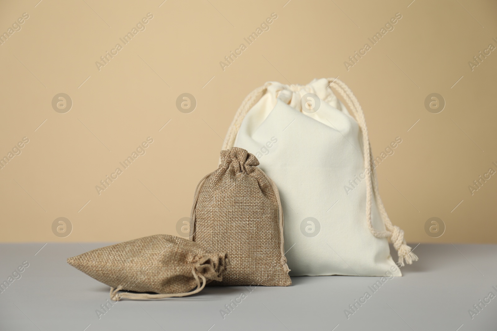 Photo of Burlap and cotton bags on grey table against beige background