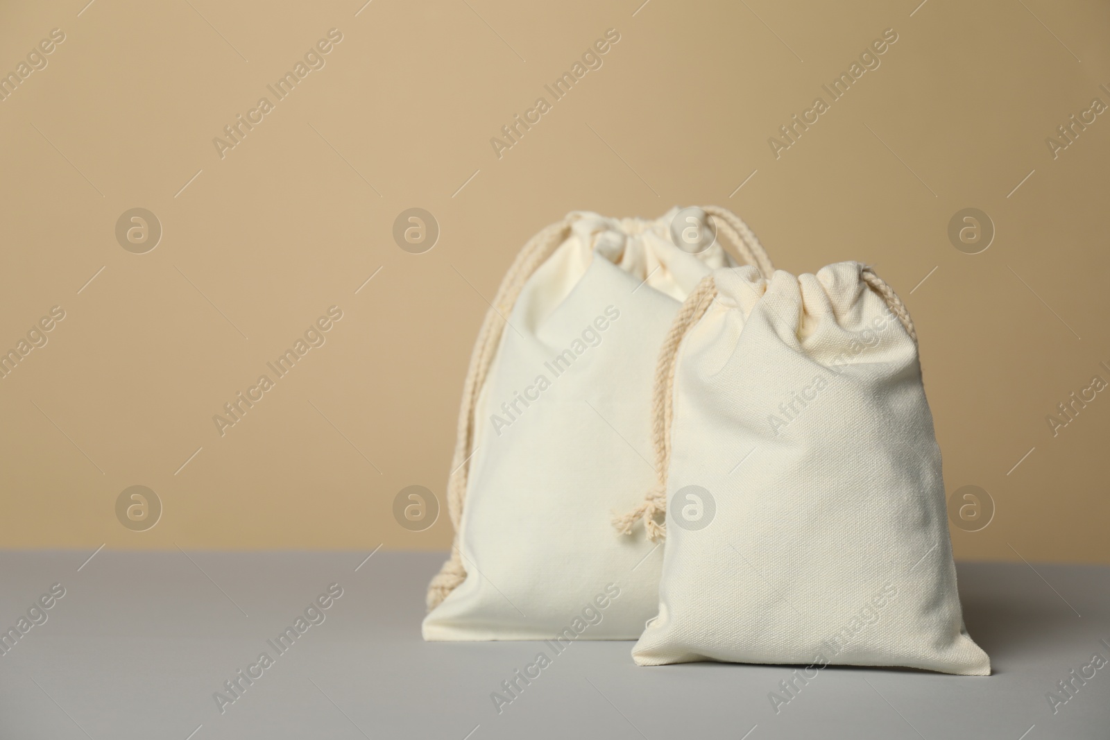 Photo of Cotton bags on grey table against beige background, space for text