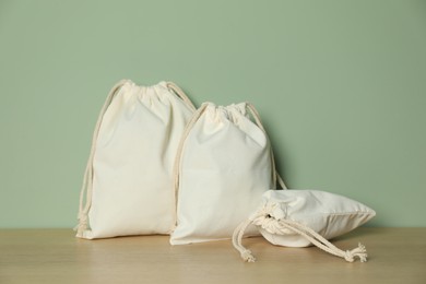 Photo of Cotton bags on wooden table against green background