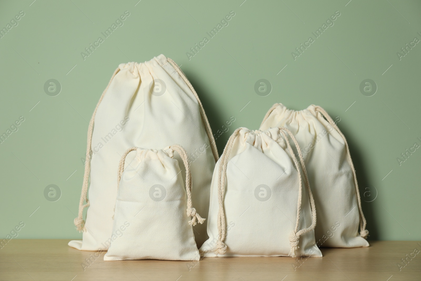 Photo of Cotton bags on wooden table against green background