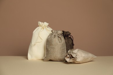 Different burlap bags on table against dark beige background