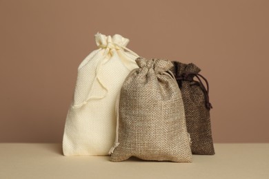 Different burlap bags on table against dark beige background