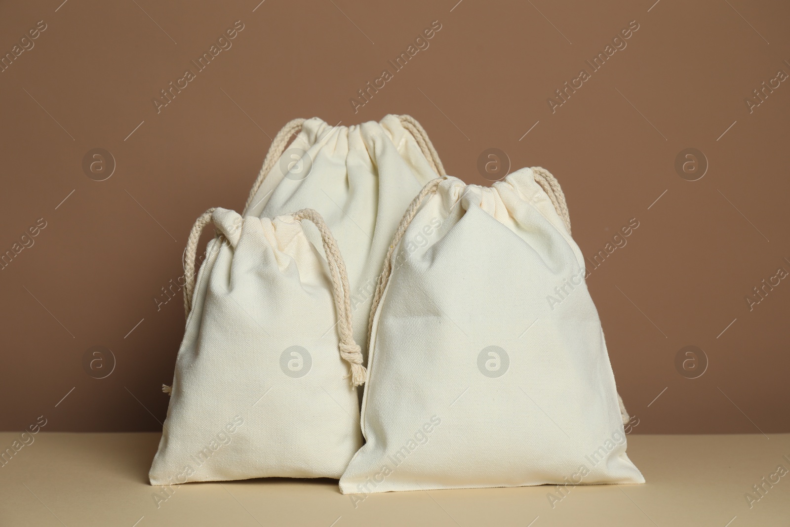 Photo of Different cotton bags on table against dark beige background