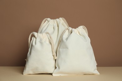 Photo of Different cotton bags on table against dark beige background