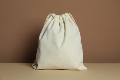 Photo of One cotton bag on table against dark beige background