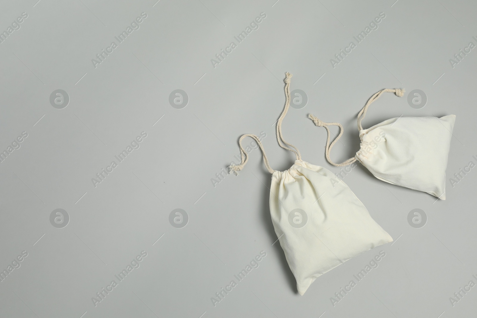 Photo of Cotton bags on grey background, flat lay. Space for text