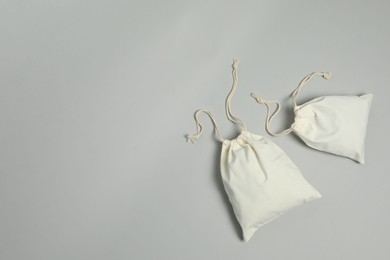 Photo of Cotton bags on grey background, flat lay. Space for text