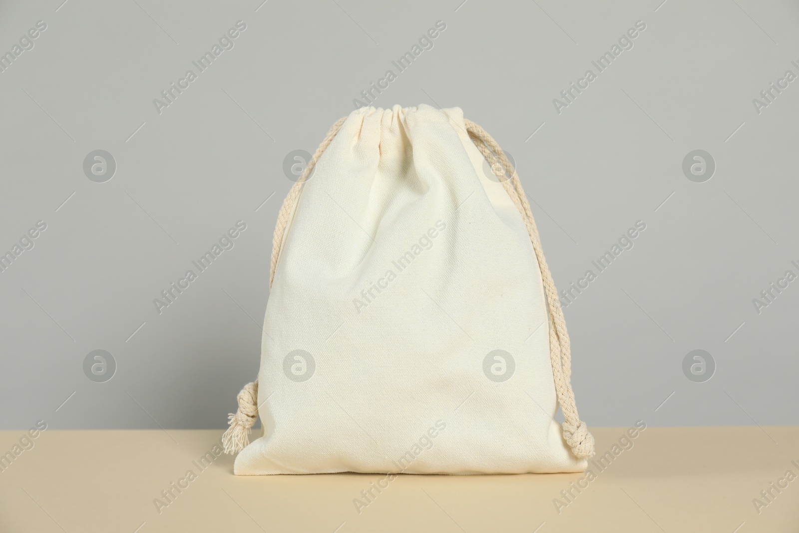 Photo of One cotton bag on beige table against grey background