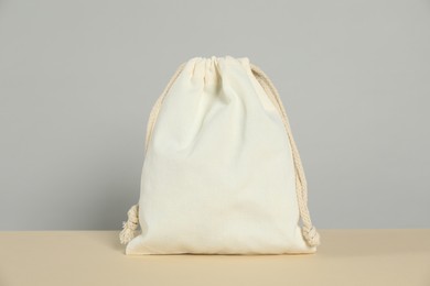 Photo of One cotton bag on beige table against grey background