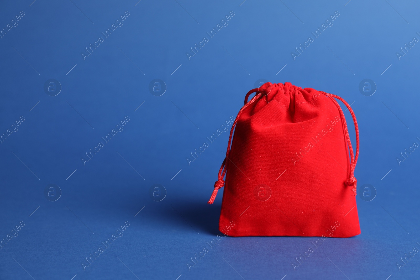 Photo of One red cotton bag on blue background, closeup. Space for text