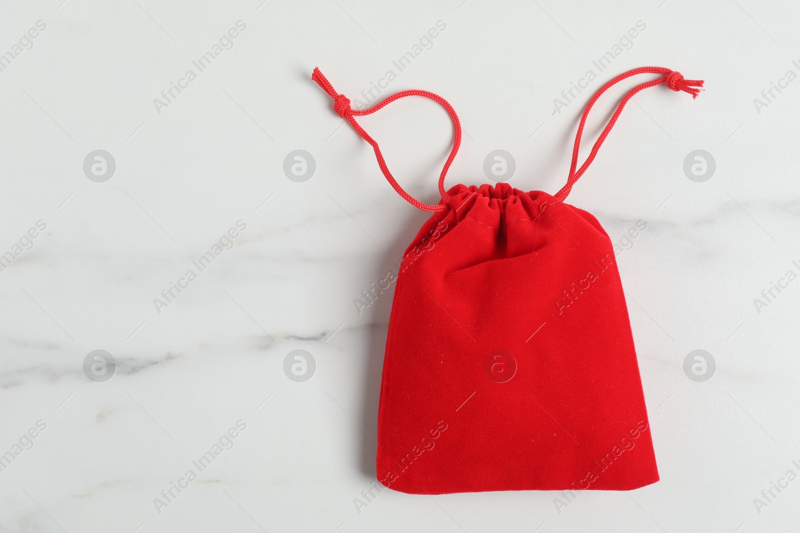 Photo of One red cotton bag on white marble table, top view