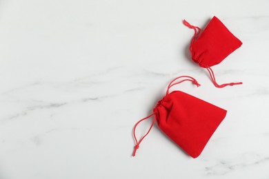 Photo of Red cotton bags on white marble table, flat lay. Space for text