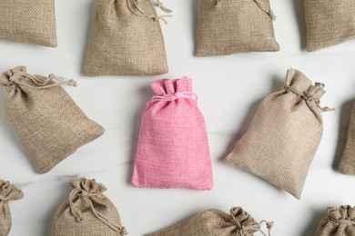 Photo of Different burlap bags on white marble table, flat lay