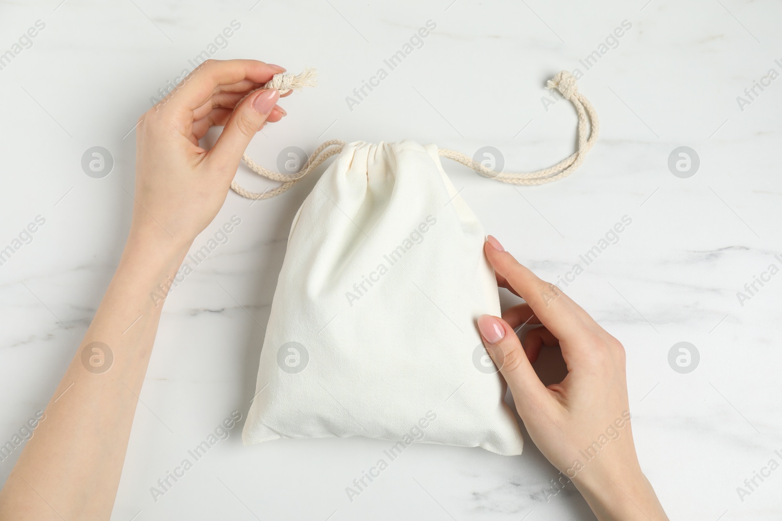 Photo of Woman with cotton bag at white marble table, top view