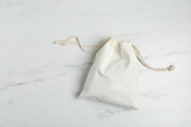 Photo of One cotton bag on white marble table, top view. Space for text