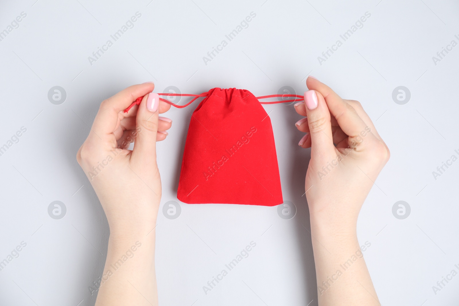 Photo of Woman with red cotton bag on light background, top view