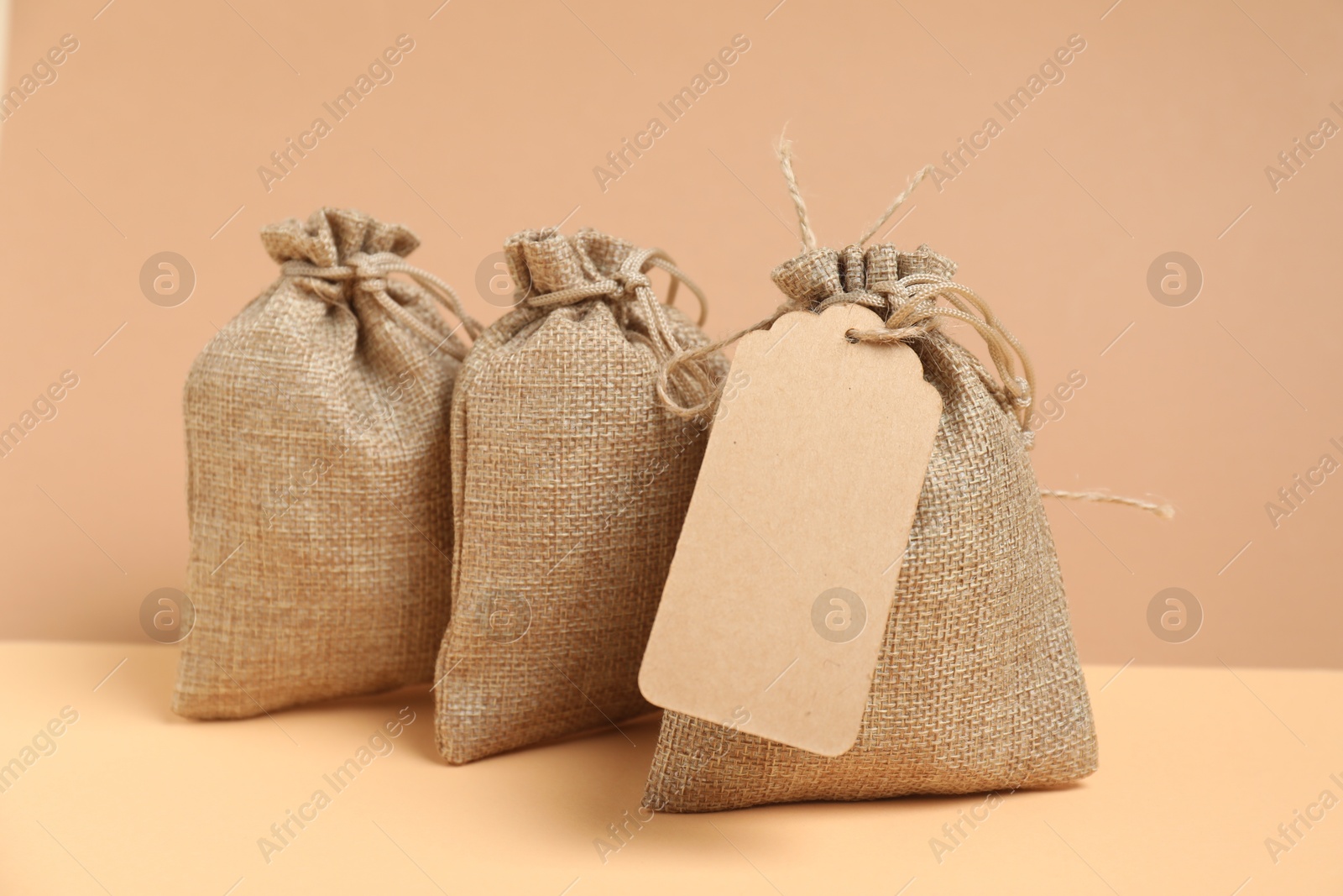 Photo of Burlap bags on table against beige background