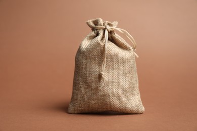 Photo of One beige burlap bag on brown background