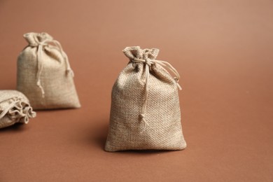 Photo of Three beige burlap bags on brown background