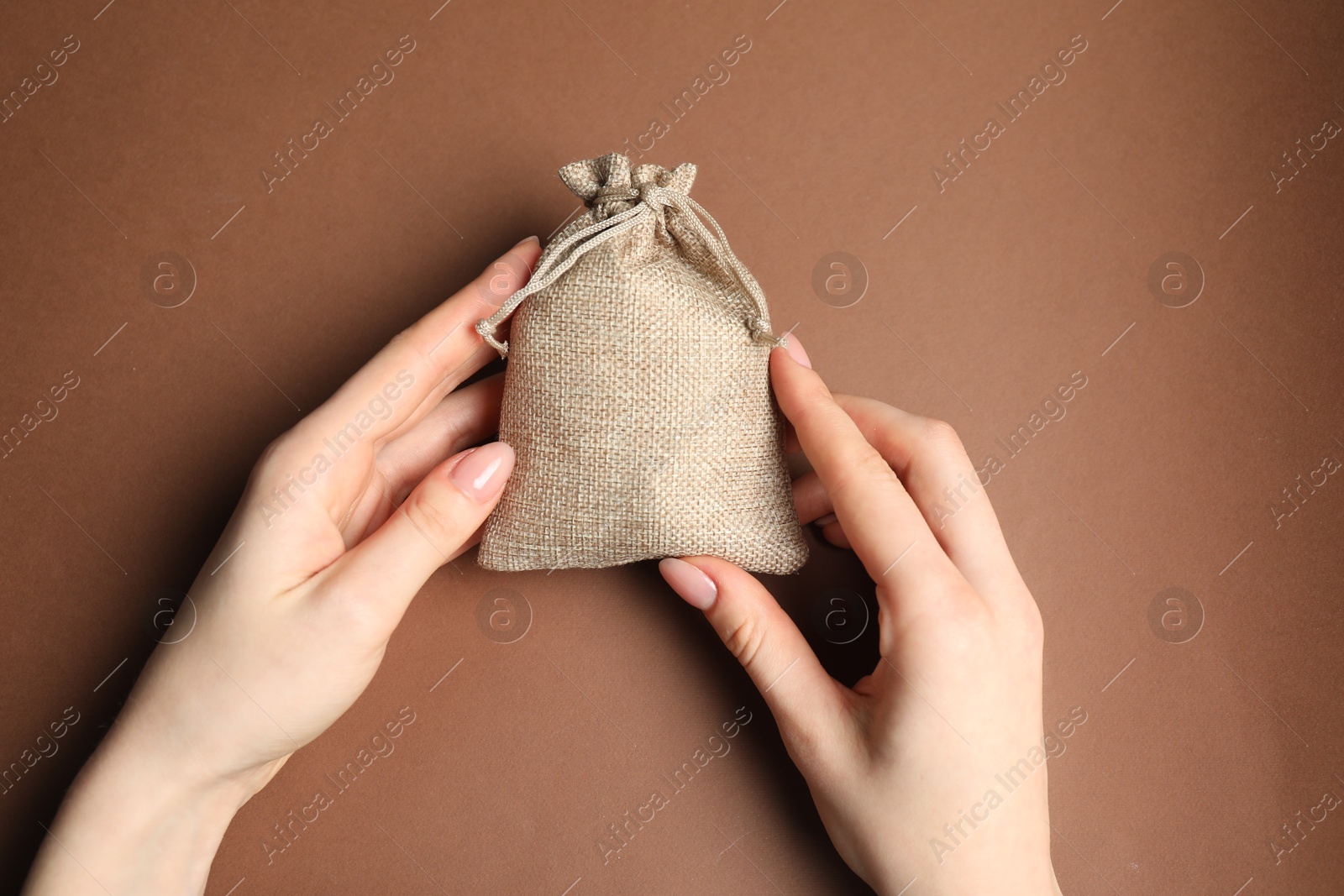 Photo of Woman with burlap bag on brown background, top view