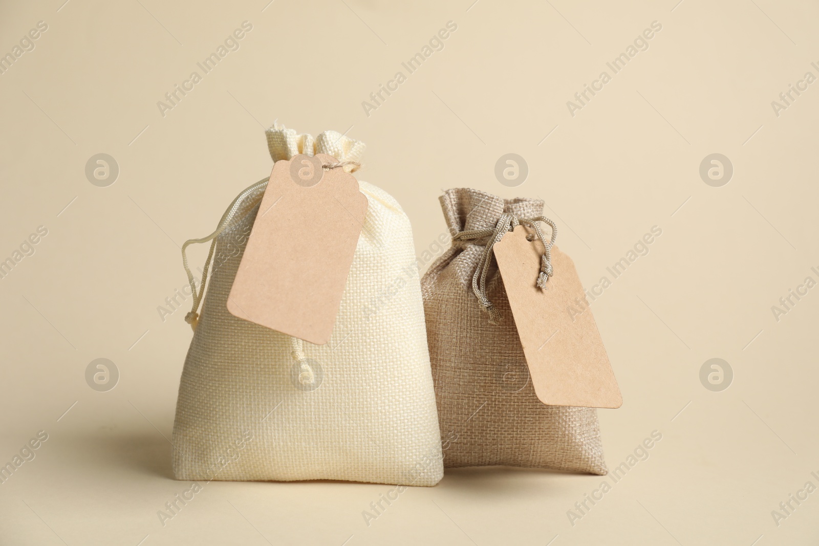 Photo of Burlap bags with tags on beige background