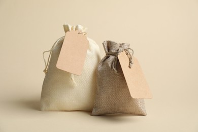 Photo of Burlap bags with tags on beige background