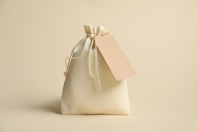 Photo of One burlap bag with tag on beige background