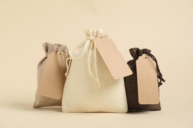 Photo of Burlap bags with tags on beige background