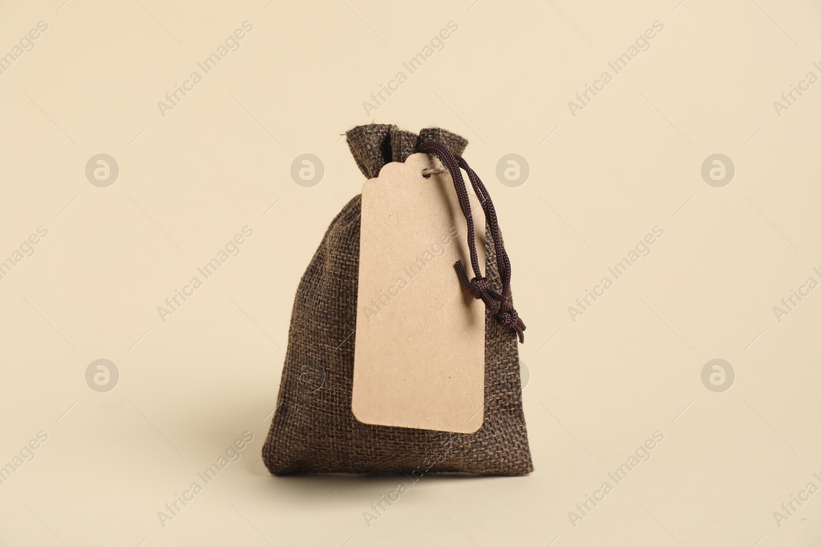 Photo of One burlap bag with tag on beige background