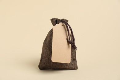 Photo of One burlap bag with tag on beige background