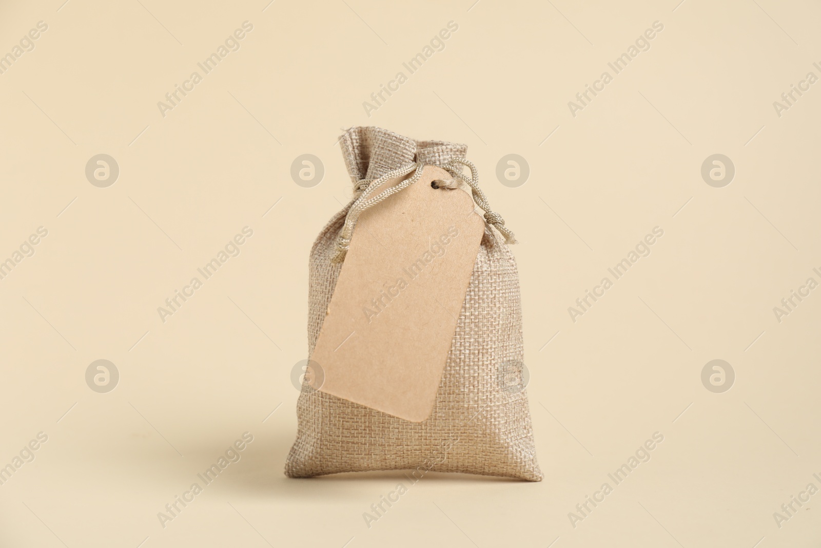 Photo of One burlap bag with tag on beige background