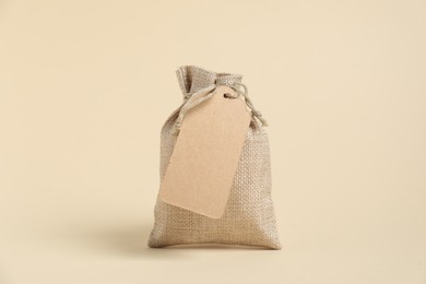 One burlap bag with tag on beige background