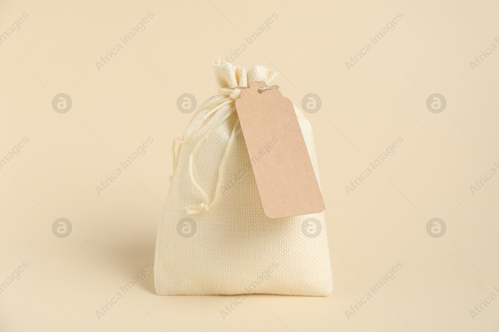 Photo of One burlap bag with tag on beige background