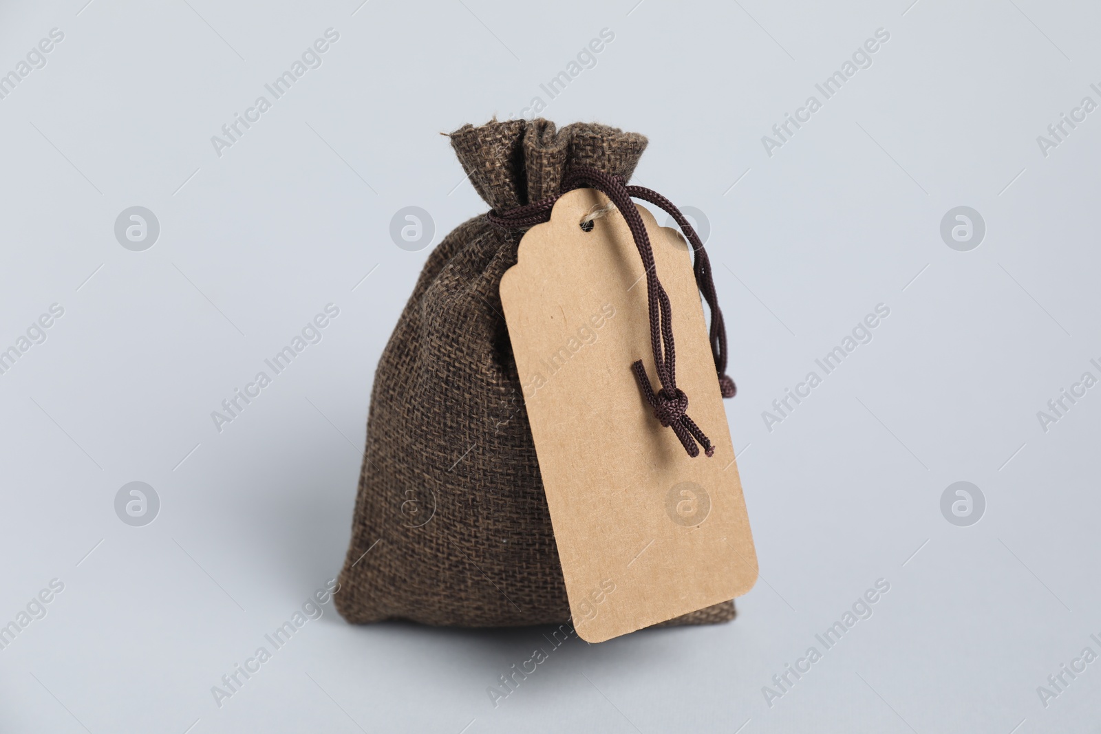 Photo of One burlap bag with tag on light background