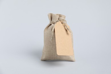 Photo of One burlap bag with tag on light background