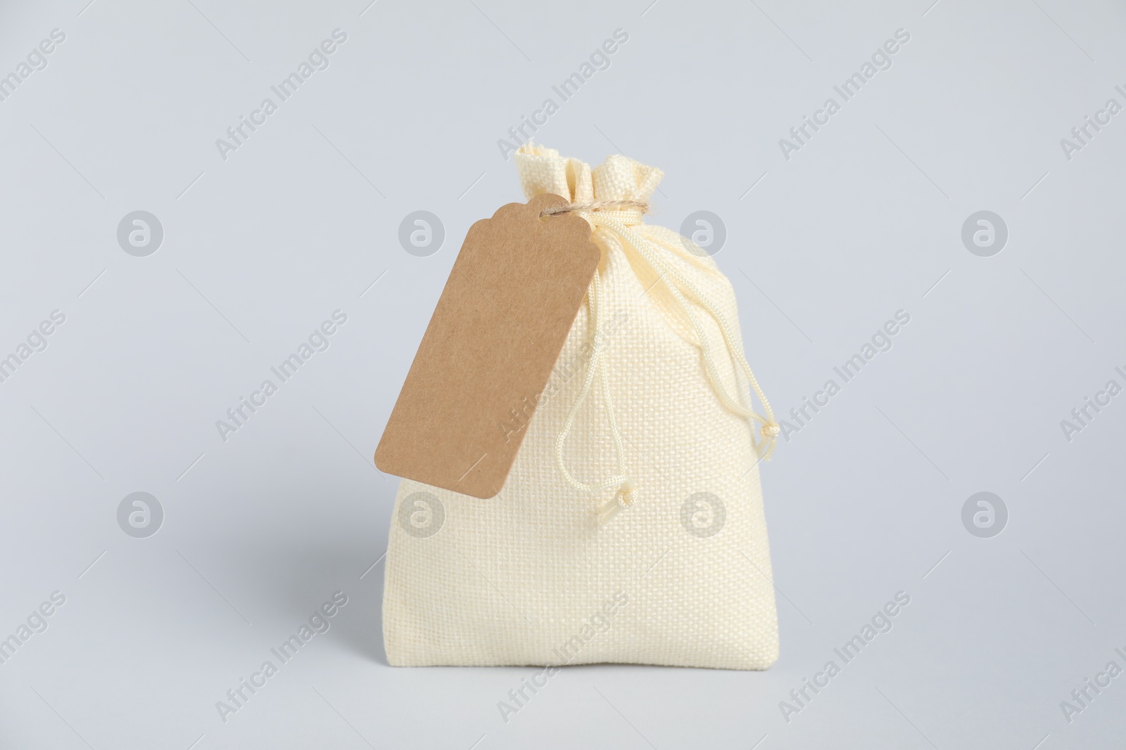 Photo of One burlap bag with tag on light background