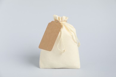 Photo of One burlap bag with tag on light background